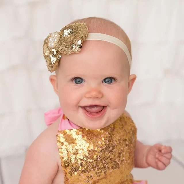 Gold sequin bow decorated with a beautiful pearl and diamante rhinestone on a soft elastic headband